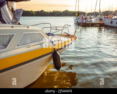 Festgemacht vintage Segelyacht auf einem Steg am Abend in goldener Stunde mit Reflexion im Wasser Stockfoto