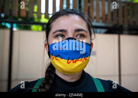 Bangkok, Thailand. 20. April 2022. Eine Frau trägt eine Gesichtsmask mit den Farben der ukrainischen Flagge, die mit einer Anti-Kriegs-Botschaft bedeckt ist. Demonstranten versammelten sich in Bangkok, Thailand, in der Nähe der russischen Botschaft, um ihre Opposition gegen den russischen Krieg in der Ukraine auszudrücken. Thailand ist in Bezug auf den Krieg in der Ukraine offiziell neutral geblieben, nachdem es sich bei der UN-Resolution, die den Krieg Anfang März 2022 verurteilte, der Stimme enthalten hatte. Kredit: SOPA Images Limited/Alamy Live Nachrichten Stockfoto