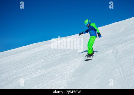 Snowboarder Boy geht mit Snowboard auf der Skipiste bergab Stockfoto