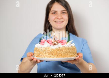 Der Arzt oder die Krankenschwester hält zum Jahrestag der Eröffnung der Klinik einen Geburtstagskuchen mit der Nummer sechs Stockfoto