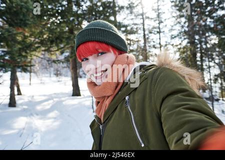 Portrait of Joyful gen Z kaukasischen Mädchen mit roten Haaren Aufnahme Selfie-Foto im Freien am Wintertag lächelt an der Kamera Stockfoto