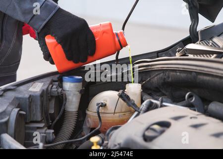 Auto-Meister Mechaniker Gießen Frostschutzmittel in Expansionstank bei Kfz-Service-Werkstatt Stockfoto