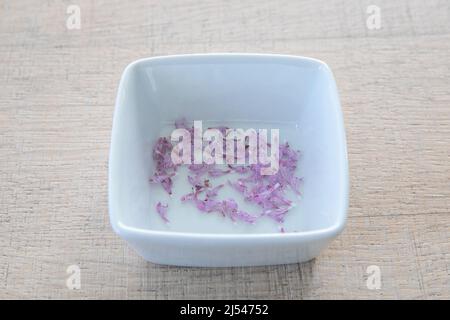 Frische, rote, tote Brennnessel, lamium purpureum. Frische Blumen, rosa Blütenblätter auf einem Küchentisch in einem weißen Becher. Handgepflückte Blumen, medizinisch Stockfoto