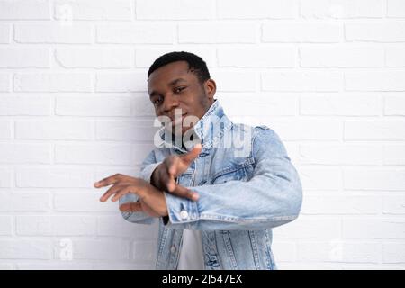 Portrait junger hübscher afrikanischer schwarzer Mann, der Jeansjacke an Backstein trägt und im Freien eine Wand mit Copyspace hat. Stockfoto