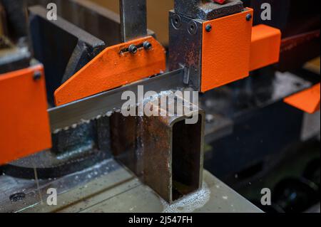 Der Prozess des Schneidens eines Metallprofils auf Bandsägemaschine Stockfoto