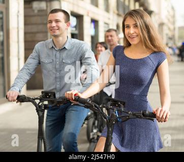 Freunde von Touristen verschiedener Generationen genießen eine Fahrt mit Elektrorollern Stockfoto