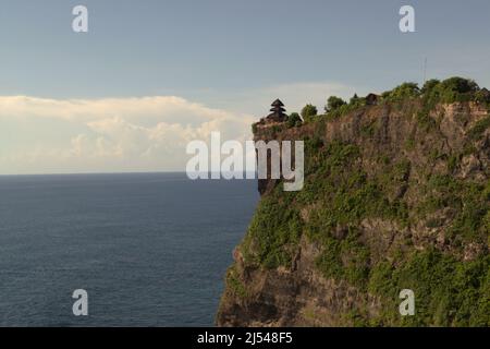 Eine Klippe am Meer mit einem Hindu-Tempel (Pura Luhur/Luhur-Tempel), der auf ihm in Uluwatu, Badung, Bali, Indonesien, errichtet wird. Stockfoto