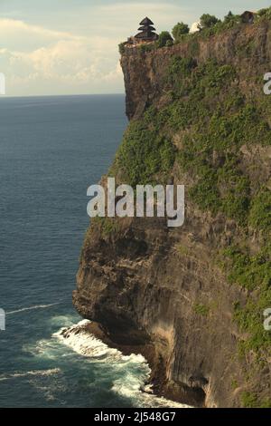 Eine Klippe am Meer mit einem Hindu-Tempel (Pura Luhur/Luhur-Tempel), der auf ihm in Uluwatu, Badung, Bali, Indonesien, errichtet wird. Stockfoto