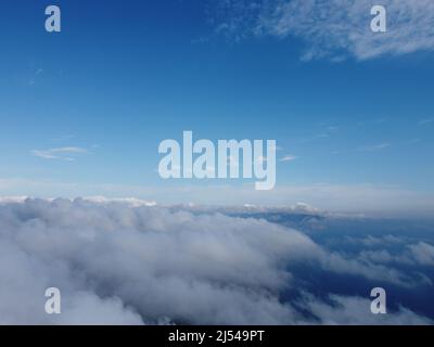 Hoch über dem dichten Nebel, wie ein wunderschönes Wolkenmeer bei Sonnenaufgang. Die Sonne geht über dem endlosen Wolkenmeer bis zum Horizont auf. Atemberaubende Natur Stockfoto