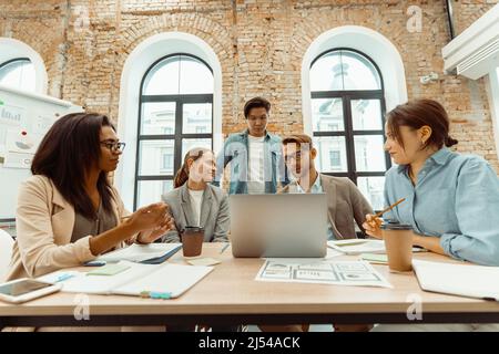 Junge Leute, die im Büro auf Laptop-sreen schauen Stockfoto