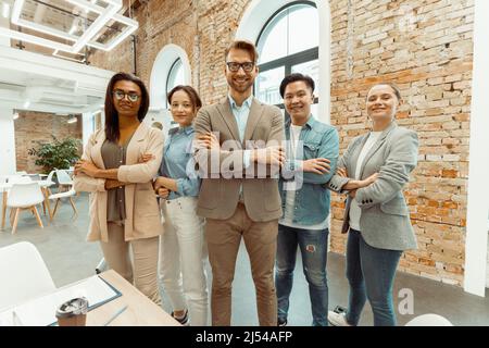 Glückliche Geschäftsleute mit gekreuzten Armen im Büro Stockfoto