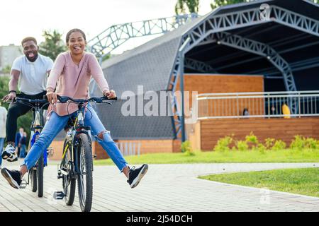 Lachendes junges Paar, das in der Innenstadt Fahrräder reitet Stockfoto