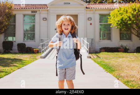 Kinderpuppe mit Rucksäcken im Park in der Nähe der Schule. Schuljunge mit Rucksäcken im Freien. Wissenstag. Schuluniform. Stockfoto