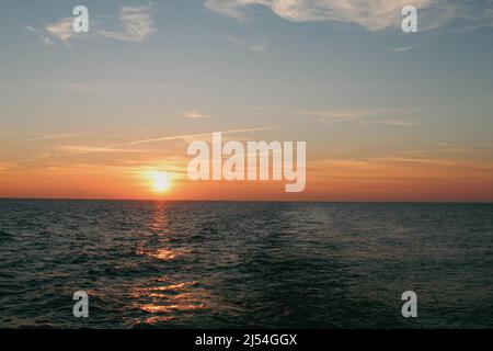 Die Sonne geht über den ruhigen Gewässern der Ostsee unter Stockfoto