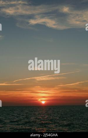 Die Sonne geht über den ruhigen Gewässern der Ostsee unter Stockfoto