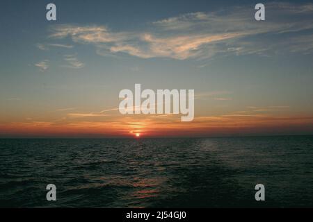 Die Sonne geht über den ruhigen Gewässern der Ostsee unter Stockfoto