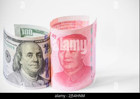 DIE BANKNOTE DES US-Dollars und des chinesischen Yuan steht auf weißem Hintergrund Stockfoto