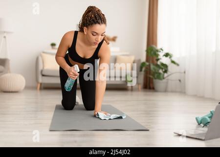 Afrikanische Weibliche Reinigung Gymnastik Matte Sanitizing Ausrüstung Vor Dem Training In Der Halle Stockfoto