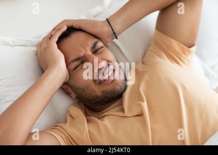 Arabischer Mann, Der Kopfschmerzen Hat, Liegt Im Bett Drinnen, Oberhalb Der Ansicht Stockfoto