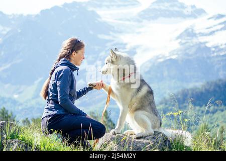 Hund mit einer Frau, die im Freien in die Berge läuft Stockfoto