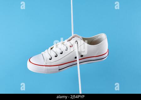 Weiße, lässige Sneakers auf blauem Hintergrund, kreativer Minimalismus Stockfoto