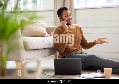 Lächelnder Mann, der zu Hause telefoniert und arbeitet Stockfoto