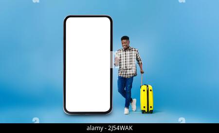 Tourist Guy Mit Mobiltelefon In Der Nähe Von Riesigen Smartphone, Blauer Hintergrund Stockfoto