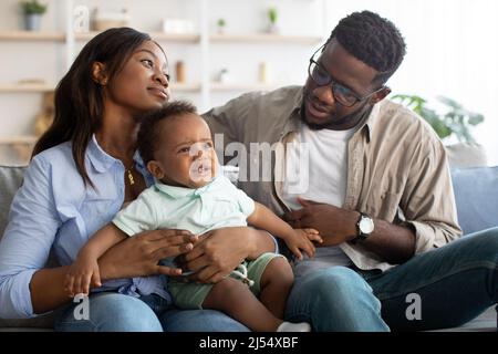 Afroamerikanische Eltern trösten weinendes Kind auf dem Sofa Stockfoto