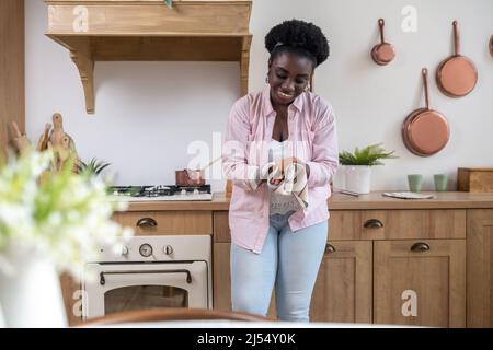 Zufriedene afrikanische Frau in rosa Kleidung trocknet Hände Stockfoto