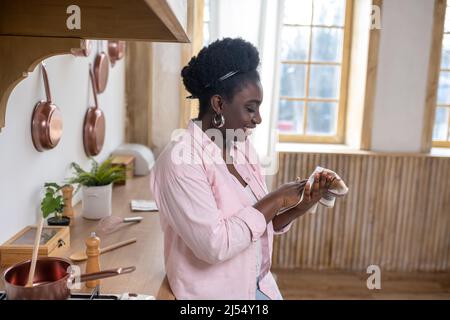 Zufriedene afrikanische Frau in rosa Kleidung trocknet Hände Stockfoto