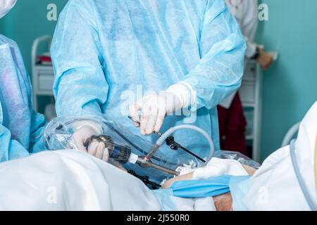 Selektiver Fokus auf die Hände von Chirurgen, die laparoskopische chirurgische Geräte manipulieren. Chirurgische Behandlung proktologischer Erkrankungen durch Punktionen in der Bauchhöhle. Stockfoto