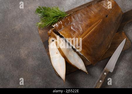 Frisch geräucherter Heilbutt auf braunem Hintergrund geschnitten. Blick von oben. Gesunde Omega-3 ungesättigte Fette gut für Gehirn und geistige Klarheit. Stockfoto