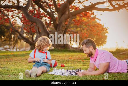 Fröhliche Familie im Freien. Vater und Sohn spielen Schach im Herbstgarten. Stockfoto
