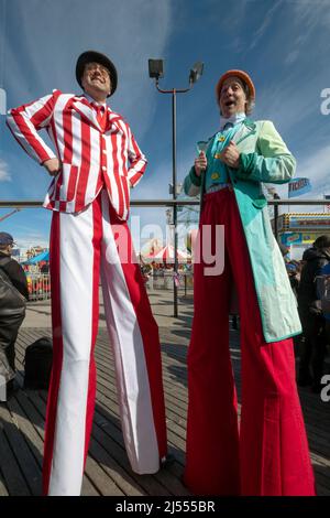 Männer auf Stelzen bei der Saisoneröffnung für Deno's Wonder Wheel Amusement Park auf der Promenade in Coney Island, Brooklyn, New York City, Stockfoto