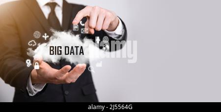 Geschäftsmann hält die Inschrift , Wort BIG DATA . Vorhängeschloss, Gehirn, Mann, Planet, Graph, Lupe, Zahnräder, Symbol für Cloud, Grid, Dokument, Brief, Telefon Stockfoto