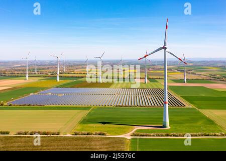 Erzeugung erneuerbarer Energie mit Windturbinen und Solarpark zwischen Feldern aus Sicht einer Panorama-Drohne Stockfoto