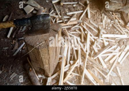 Foto einer Axt auf einen Hintergrund genagelt und Holz auf dem Boden geschnitten, um in den Lagerraum platziert werden. Landleben. Kopierraum. Hintergrund Stockfoto