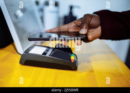 Nahaufnahme der afroamerikanischen Männer, die für eine Krankenversicherung im Krankenhaus bezahlen, bei kontaktloser Bezahlung Stockfoto
