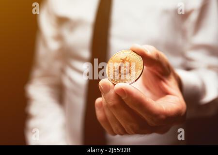 Geschäftsmann, der Bitcoin-Kryptowährungszahlung anbietet, Nahaufnahme der männlichen Hand, die Münze hält, selektiver Fokus Stockfoto