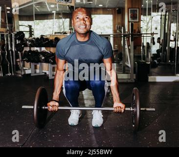 Foto von einem schwarzen Mann tun Push-ups mit einem Gewicht bar. Sport und Freizeit Stockfoto