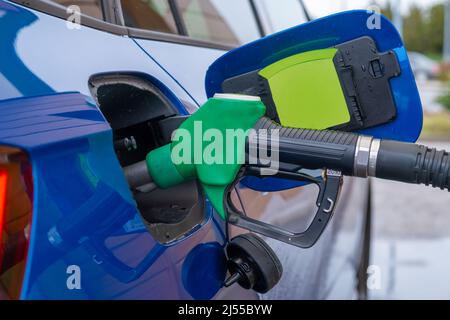 Auffüllen des blauen modernen Autos an der Tankstelle mit Benzin. Steigende Preise. Sanktion gegen die Russische Föderation und Ölembargo-Konzept. Stockfoto