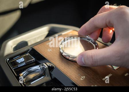 PRAG , TSCHECHISCHE REPUBLIK - MÄRZ 10 2022: Man nutzt Multimedia-Systemsteuerung im Luxuswagen BMW IX. Einstellmodus für die Hand des Fahrers in einem Fahrzeug mit stilvoller Nahansicht des Innenraums Stockfoto