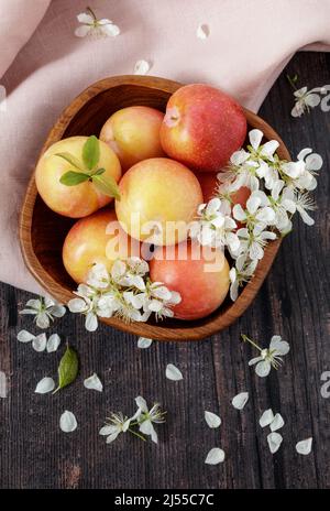 Frische gelbe Pflaumen und blühen in einer Holzschale Stockfoto