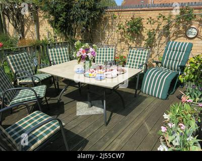 Ein Bereich der Terrasse ist ein gemeinsames Merkmal in einem englischen Garten, hier mit einem Tisch und Stühlen und Nachmittagstee wartet auf die Besucher. Stockfoto