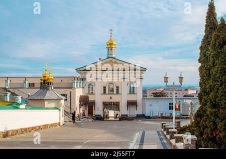 Platz mit Kopfsteinpflaster vor dem Eingang zum komplexen orthodoxen Kloster Pochaiv Lavra. Schmiedeeiserne Tore. Religiöse Gebäude. Ukraine, 2022. Stockfoto