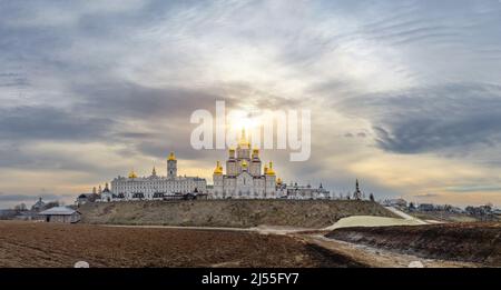 Magische Ansicht der Heiligen Dormition Pochajiv Lavra in der Ukraine. Panoramablick. Sonnenlicht über dem Kloster. Schwarze Wolken sammeln sich herum. Stockfoto