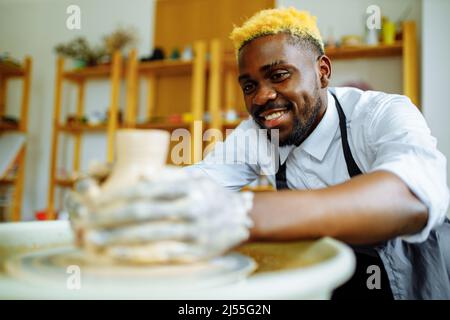 Gemischter Mann aus der Rasse, der im Töpferstudio eine Vase macht Stockfoto