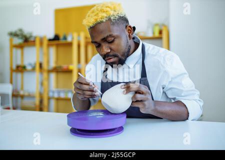 Gemischter Mann aus der Rasse, der im Töpferstudio eine Vase macht Stockfoto