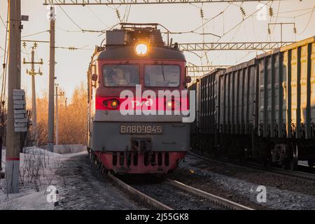 SHARYA, RUSSLAND - 19. MÄRZ 2022: Sowjetische Elektrolokomotive VL80t-1945 und Gegenzug am Märzabend. Nordbahn Stockfoto