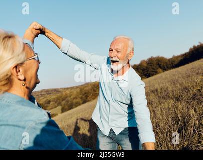 Frau Mann im Freien Senior paar glücklich Lifestyle Ruhestand zusammen lächelnd Liebe tanzen Natur reifen Stockfoto